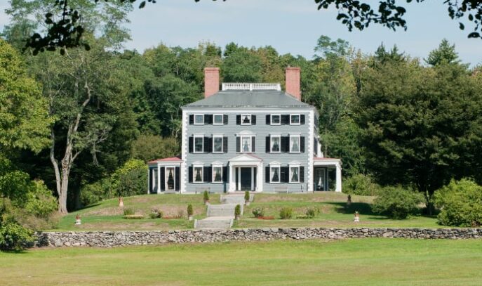Photo of the exterior of the Codman Estate. The photo is taken from quite a ways back showing a large green lawn in front.