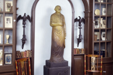 A photo inside the building showing a statue of George Washington flanked by two metal eagles on pedestals.