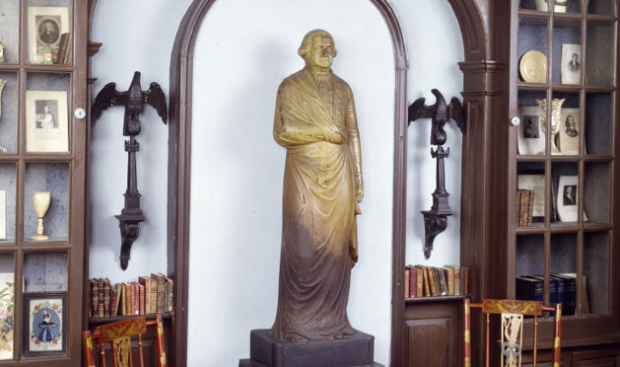 A photo inside the building showing a statue of George Washington flanked by two metal eagles on pedestals.